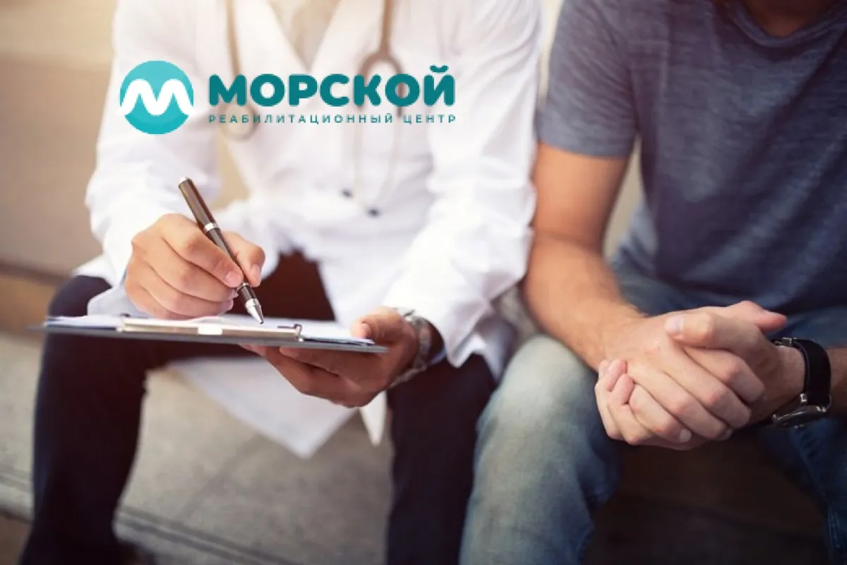 Мужчина сидит рядом с врачом и рассказывает про свои жалобы врачу - консультация с врачом