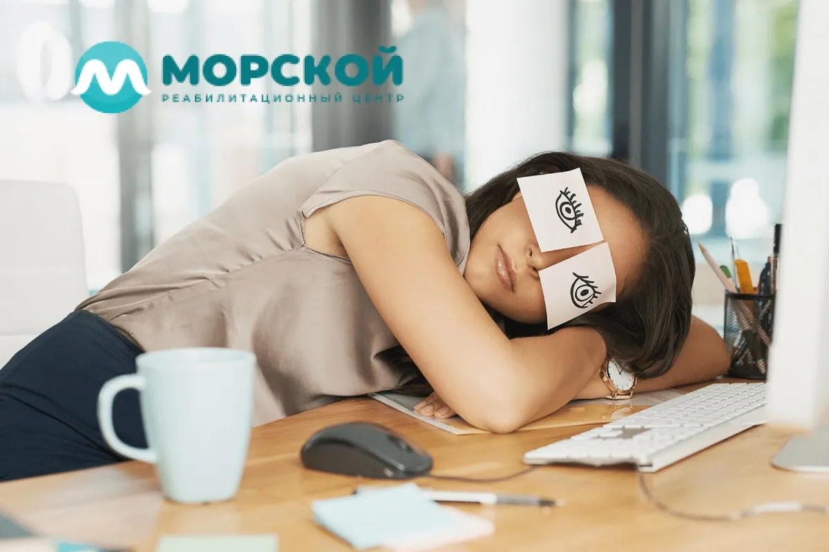 Девушка спит на рабочем месте на глаза приклеены стикеры в виде нарисованных открытых глаз