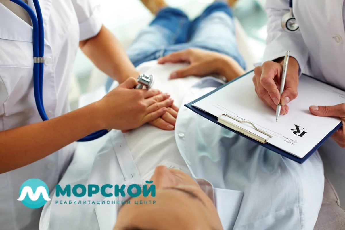 Врачи проводят обследование пациента в кабинете врача Два врача стоят перед пациенту около кушетки и проводят обследование больного